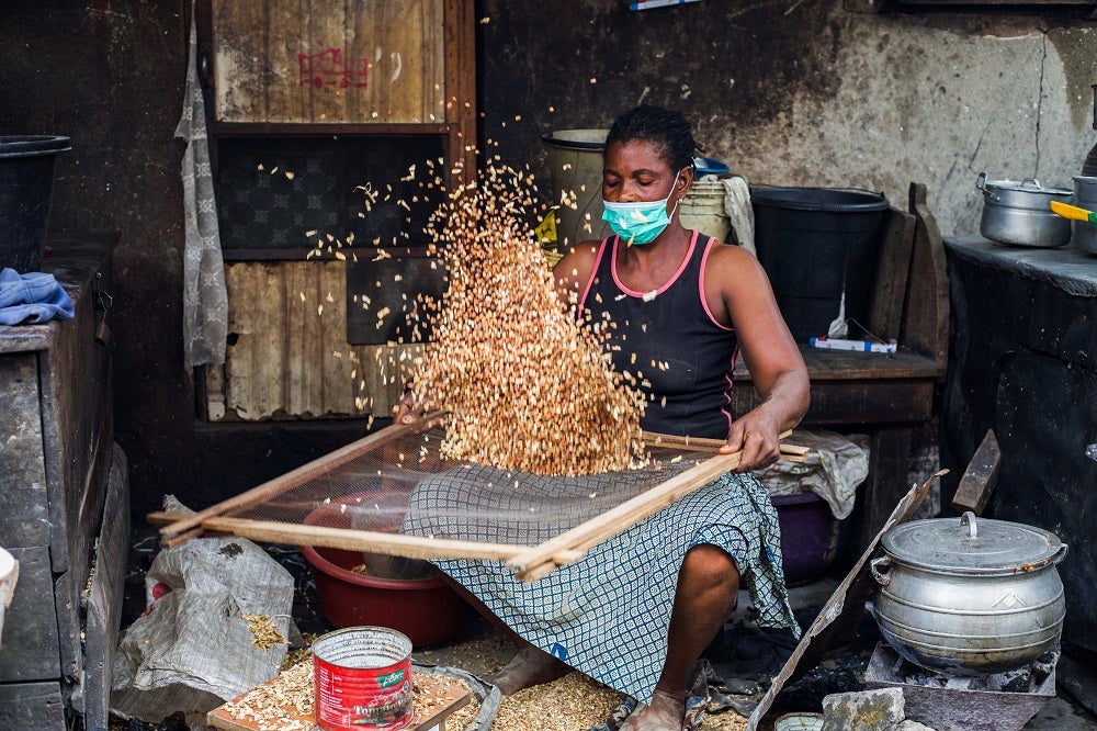 A bean seller sieves raw beans in Lagos, Nigeria