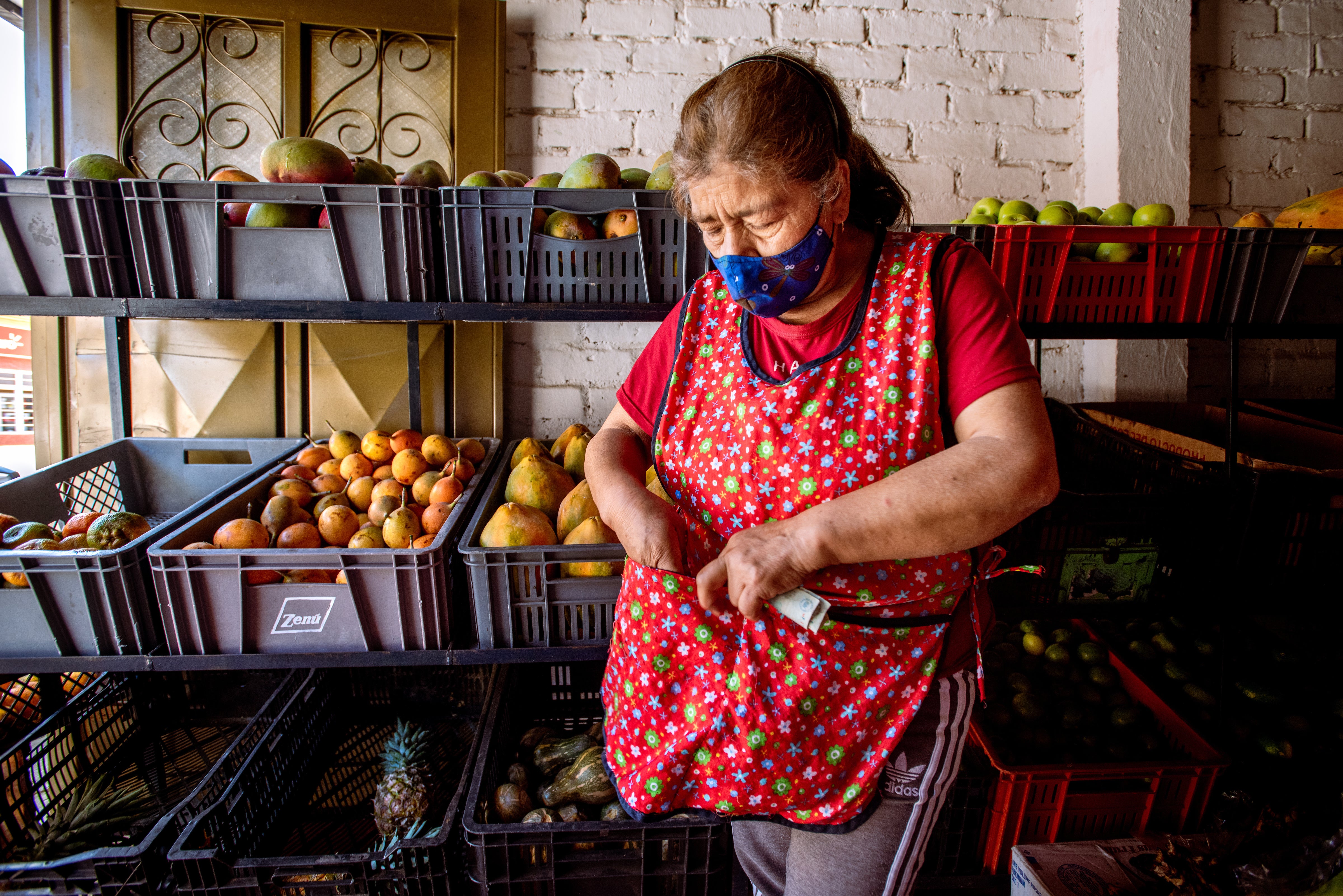 A woman stands next to her fruit stand