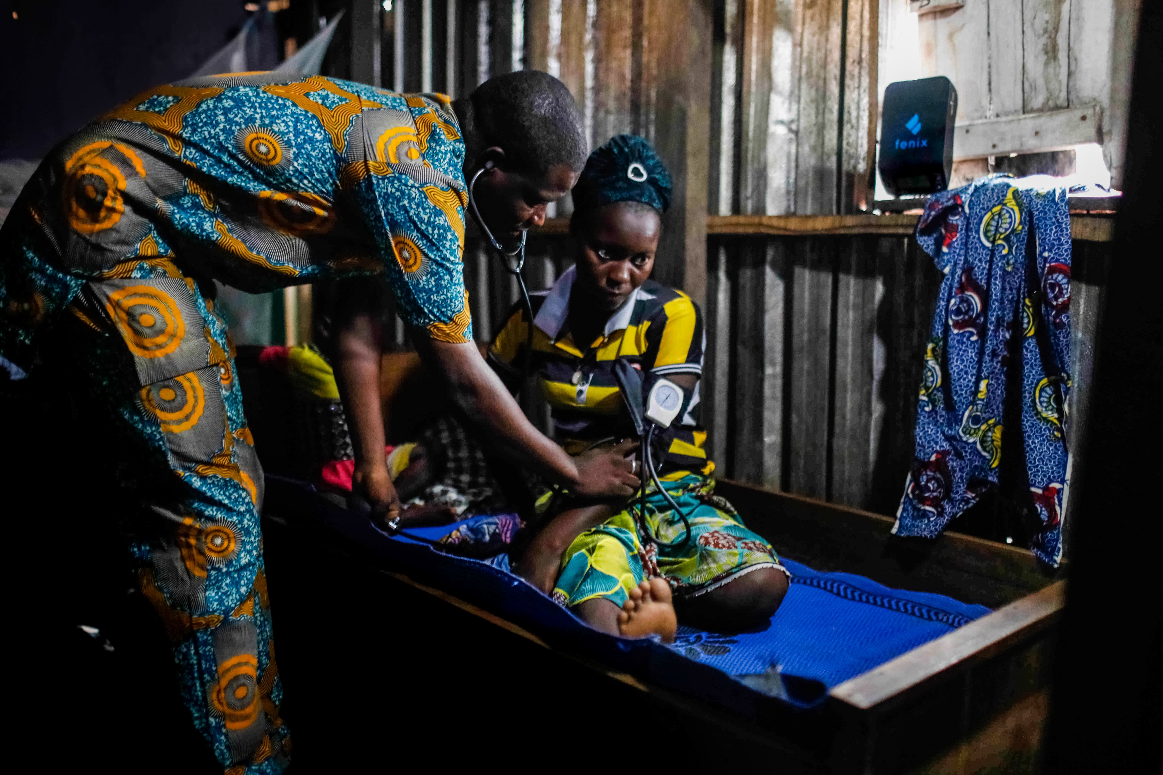 Emmanuel Kahomey attends to a patient in Lagos, Nige-ria. A financed “pay-as-you-go” (PAYGo) off-grid solar system powers his small clinic. “Using PAYGo solar is more economical than using a conventional fuel-powered generator to run the clinic,” he said. CGAP Photo: Temilade Adelaja via Communication for Development Ltd.