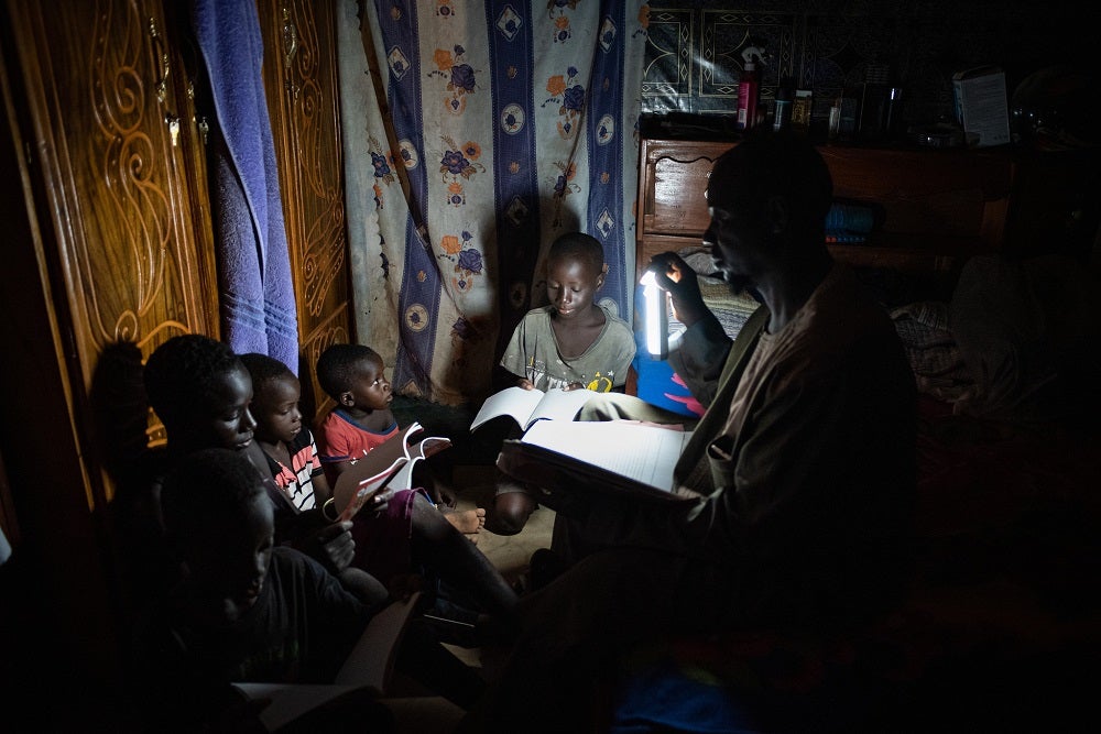 Family reads by PAYGo solar light in Mali