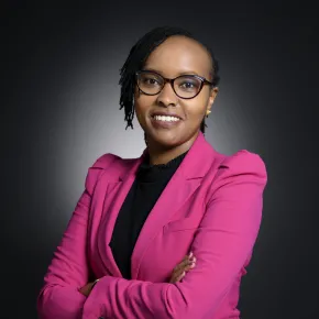 headshot of woman in pink jacket against a dark background