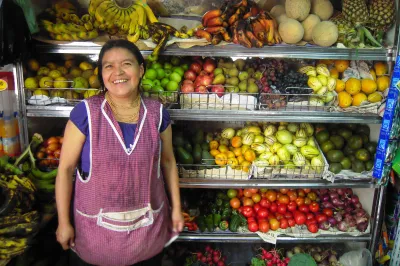 A Peruvian woman stands in front of her shop shelves full of produce
