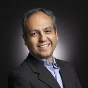 headshot of man in dark suit against black background