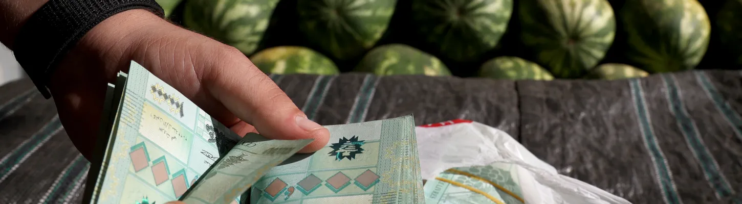 A watermelon producer counts money at a fruits and vegetables outside Beirut 