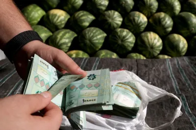 A watermelon producer counts money at a fruits and vegetables outside Beirut 