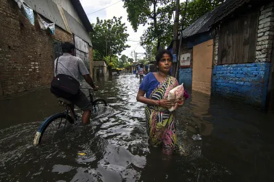 People move through a flooded street during monsoon season