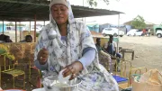 A woman scoops food at an open air market