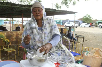 A woman scoops food at an open air market