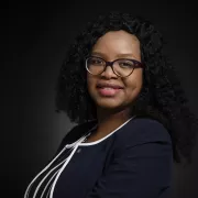 headshot of woman in black jacket against dark background