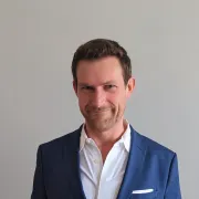 headshot of a man in blue suit against white background