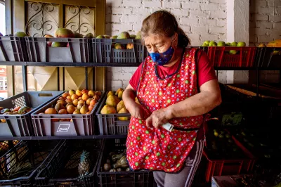 A woman stands in front of her fruit stand