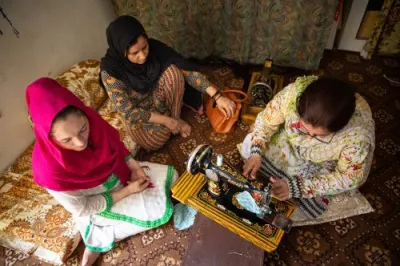 three women sitting on the ground doing tailoring and embroidery work