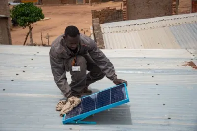 a man cleans a solar panel from a solar kit on the roof of one of the company’s customers