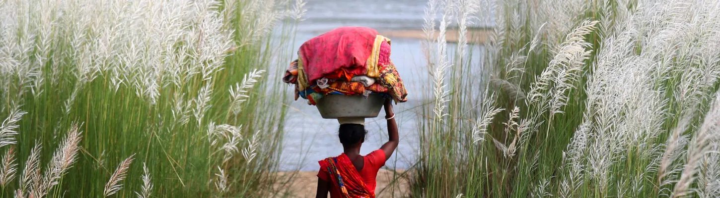 woman carrying a basket on her head walking through a field