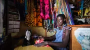 A young woman sits by her sewing machine