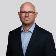 headshot of man in dark suit against white background
