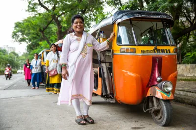 women stand outside their rickshaws