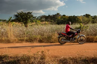 A man rides his motorcycle down an open road in rural Mozambique.