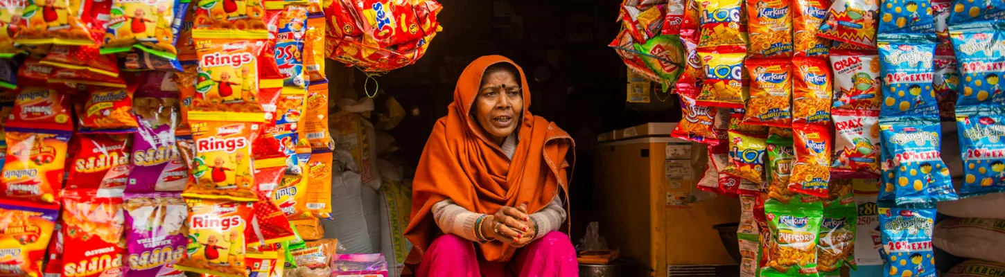 a woman in india sits in front of her small tuck shop