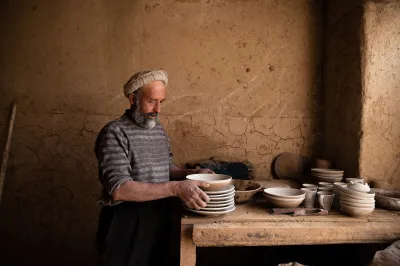A man in a ceramic workshop holds dishes