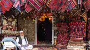 A man sits outside a rug shop