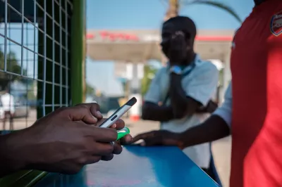 Teller holds smartphone in Zambia. Photo: Nyani Quarmyne, IFC